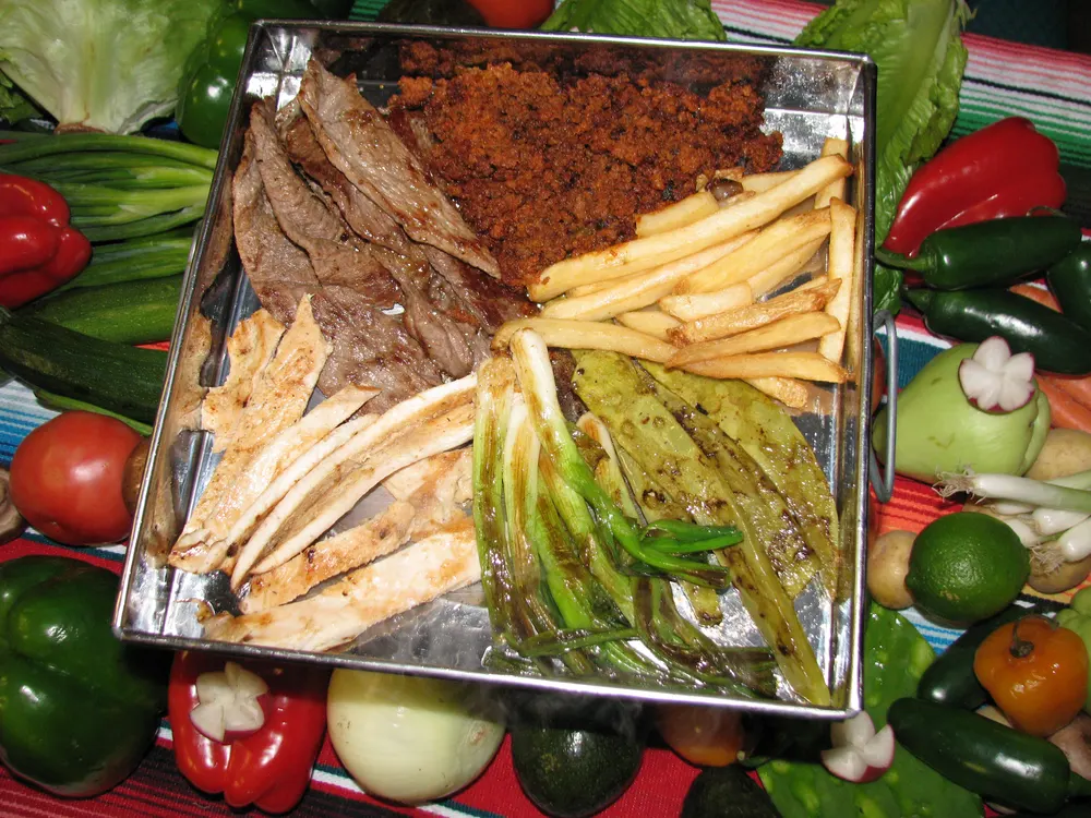 A sizzling platter with grilled peppers and onions