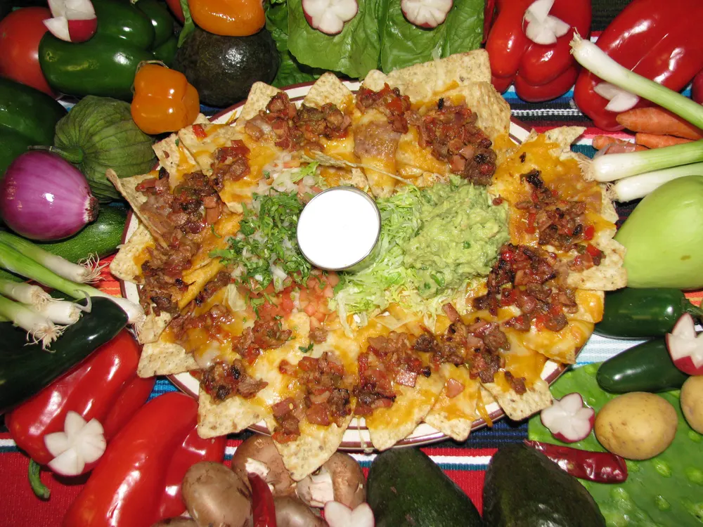 A colorful plate of nachos with guacamole and cheese